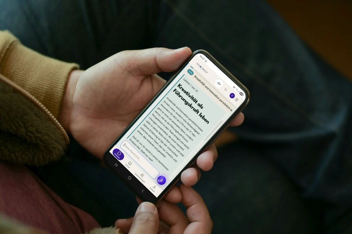Zwei Menschen im Gespräch, eine Hand hält ein Telefon mit einer Lektion der Leada-App.